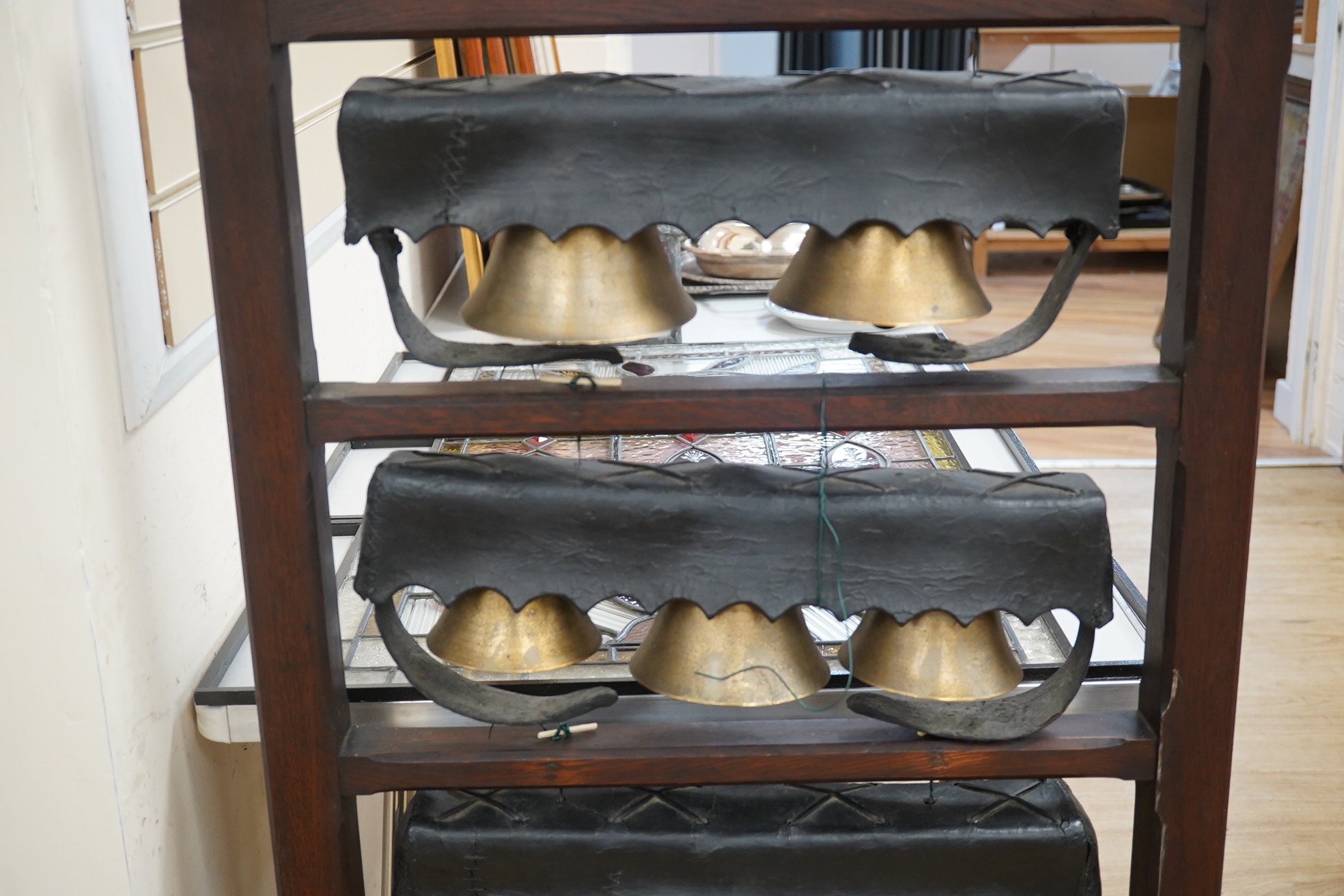 An early 20th century set of Swiss cow bells, four rows, mounted on an oak stand, 124 cm high. Condition - good